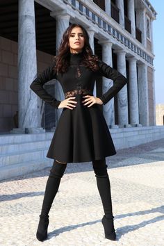 a woman standing in front of a building with her hands on her hips and wearing black boots