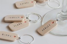 wine charms with names and hearts on them sitting next to a wine glass filled with wine