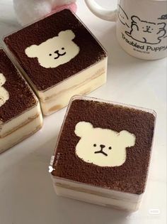 three brownies with white teddy bears on them next to a coffee cup and stuffed animal