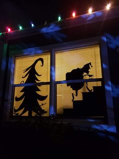 the silhouette of a horse is shown in front of a window with christmas lights on it