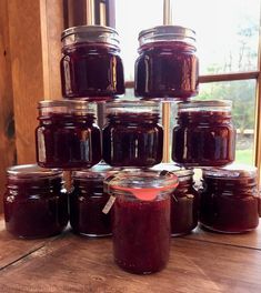 several jars of jam sit on a table in front of a window