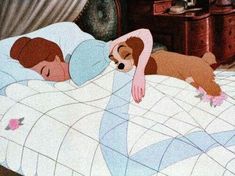 a woman laying in bed next to a dog on top of her stomach and head