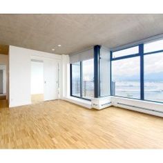 an empty room with wood floors and large windows