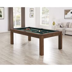 a pool table in the middle of a living room with hardwood floors and white walls