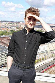 a man standing on top of a building with his hands in his hair and looking at the camera