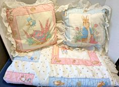 two pillows on top of each other with peter rabbit designs and pink trimmings