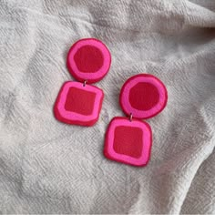 two pink earrings sitting on top of a white blanket