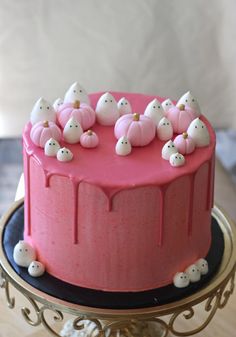 a cake with pink frosting and small white cats on top