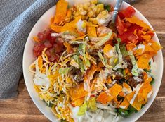 a white bowl filled with salad on top of a wooden table next to a gray napkin