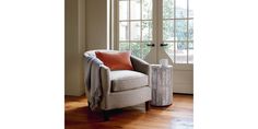 a living room with a chair, lamp and window in it's centerpiece