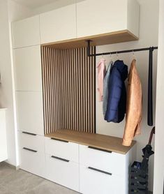 a closet with clothes hanging on the wall and coat racks in front of it,