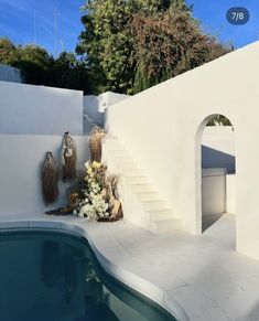 an outdoor swimming pool with steps leading up to the water's edge and flowers on the side