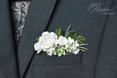 a boutonniere with white flowers and greenery on it's lapel