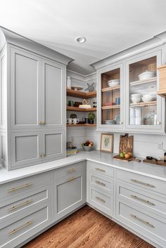 a kitchen with white cabinets and wood floors