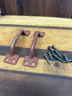 two rusted metal handles and screws on top of a wooden table next to wood planks