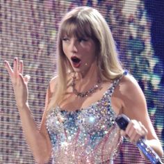 taylor swift performing on stage with her hands in the air