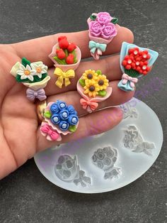 a hand holding a bunch of fake flowers on it's finger and some plastic molds