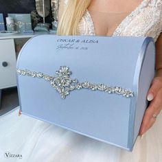 a woman is holding a blue box with a tiara on it