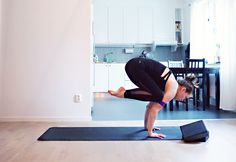 a woman is doing yoga on a mat in the middle of a room with a table and chairs