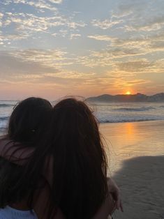 two people are hugging on the beach at sunset