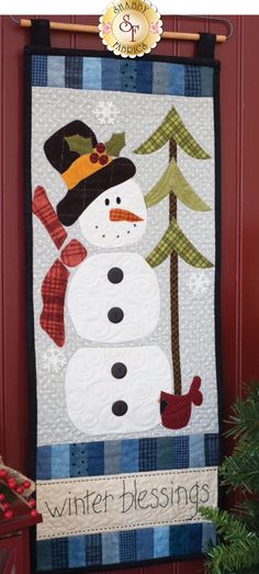 a quilted snowman hanging on the side of a red door with words winter blessing