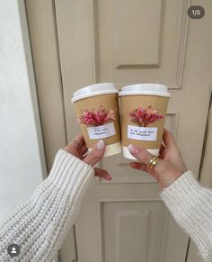 two people holding up coffee cups with flowers on them