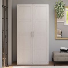 a living room with a couch, mirror and white cupboards on the wall in front of it