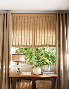 two wicker baskets sit on top of a table in front of a window with drapes