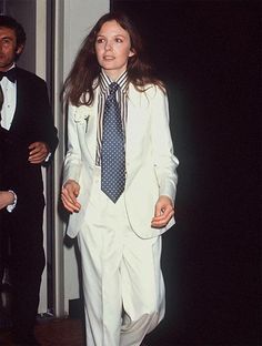 a woman in a white suit and blue tie