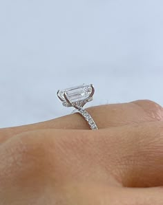 a woman's hand with a diamond ring on top of her finger and an engagement band in the middle