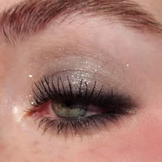 a woman's eye with long lashes and glitter on the top of her eyes