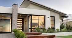 a modern house with large windows and steps leading up to the front door that leads into the yard