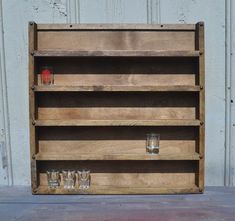 an old wooden shelf with glasses on the bottom and two empty shot glasses in front