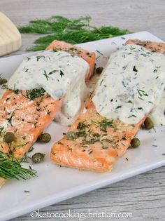 the salmon is covered in white sauce and garnished with green olives