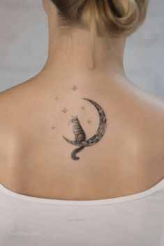 a woman with a cat sitting on the moon behind her back neck tattoo, which has stars in it