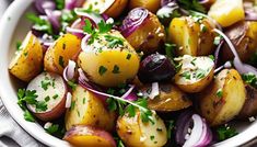 a white bowl filled with potatoes, onions and parsley on top of a table