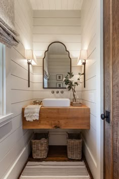 a bathroom sink sitting under a mirror on top of a wooden counter next to a door