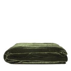 a green velvet bed spread on top of a white wall