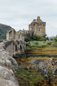 an old castle sits on the edge of a rocky cliff next to a body of water