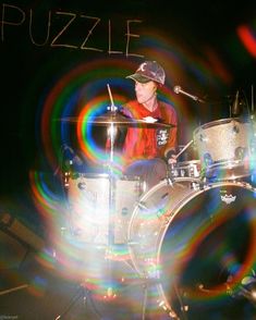 a man is playing the drums in front of a sign that says puzzle on it