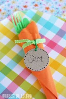 an orange carrot with a name tag on it sitting on a colorful checkered table cloth