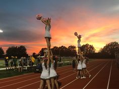 the cheerleaders are doing stunts on the track as the sun sets in the background