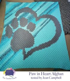 a crocheted afghan with a dog's paw and heart on the front