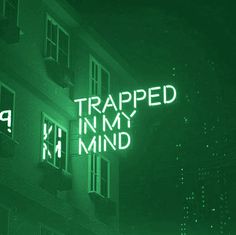 a neon sign that reads trapped in my mind on the side of a tall building