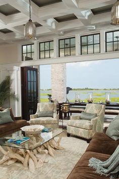 a living room with couches, chairs and a table in front of a large window