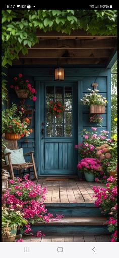 a blue door surrounded by flowers and potted plants on the steps to a porch