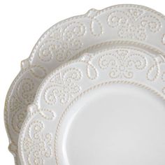 an empty white plate with intricate designs on the rim and bottom, against a white background