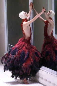 two women dressed in red and black are standing next to each other near a mirror