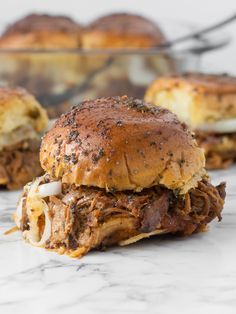 two pulled pork sliders sitting on top of a marble counter