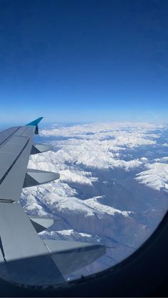 the wing of an airplane flying over snow covered mountains